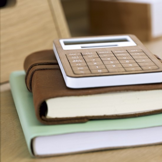 A wood-finish calculator and stacked notebooks from the feature, showing how small accessories repeat the furniture palette. Image: Ideal Home.