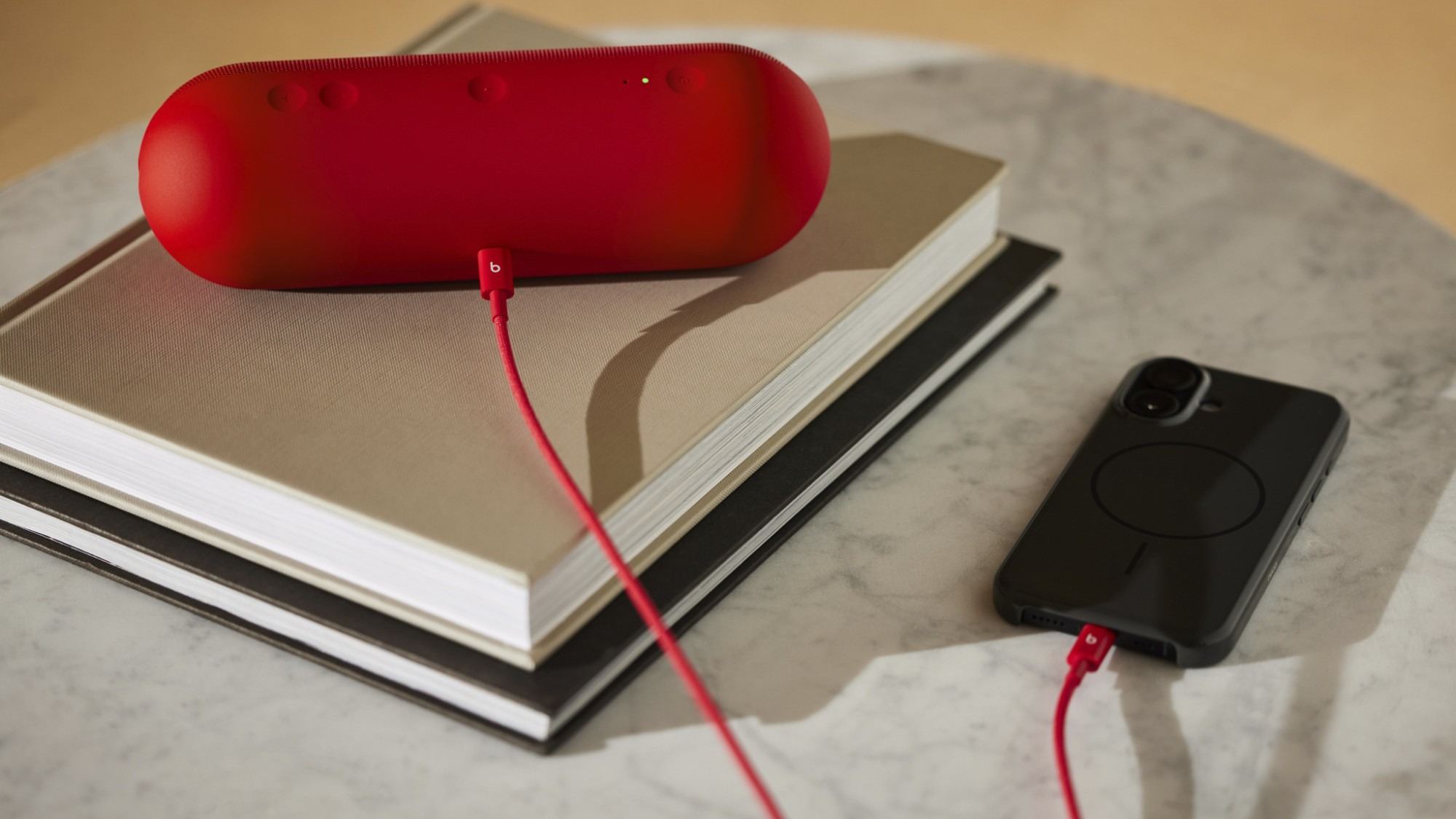 A red Beats cable connects a matching portable speaker and a phone in the source product imagery. Image: Beats / Future.