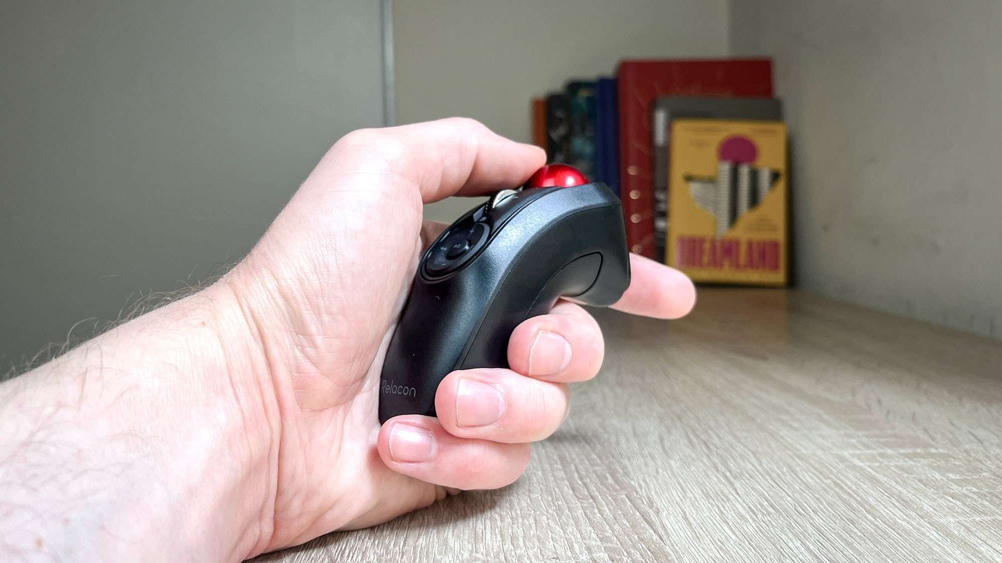 The handheld Elecom Relacon being held above a desk, showing its compact grip and red ball. Image: Alex Wawro / Future.