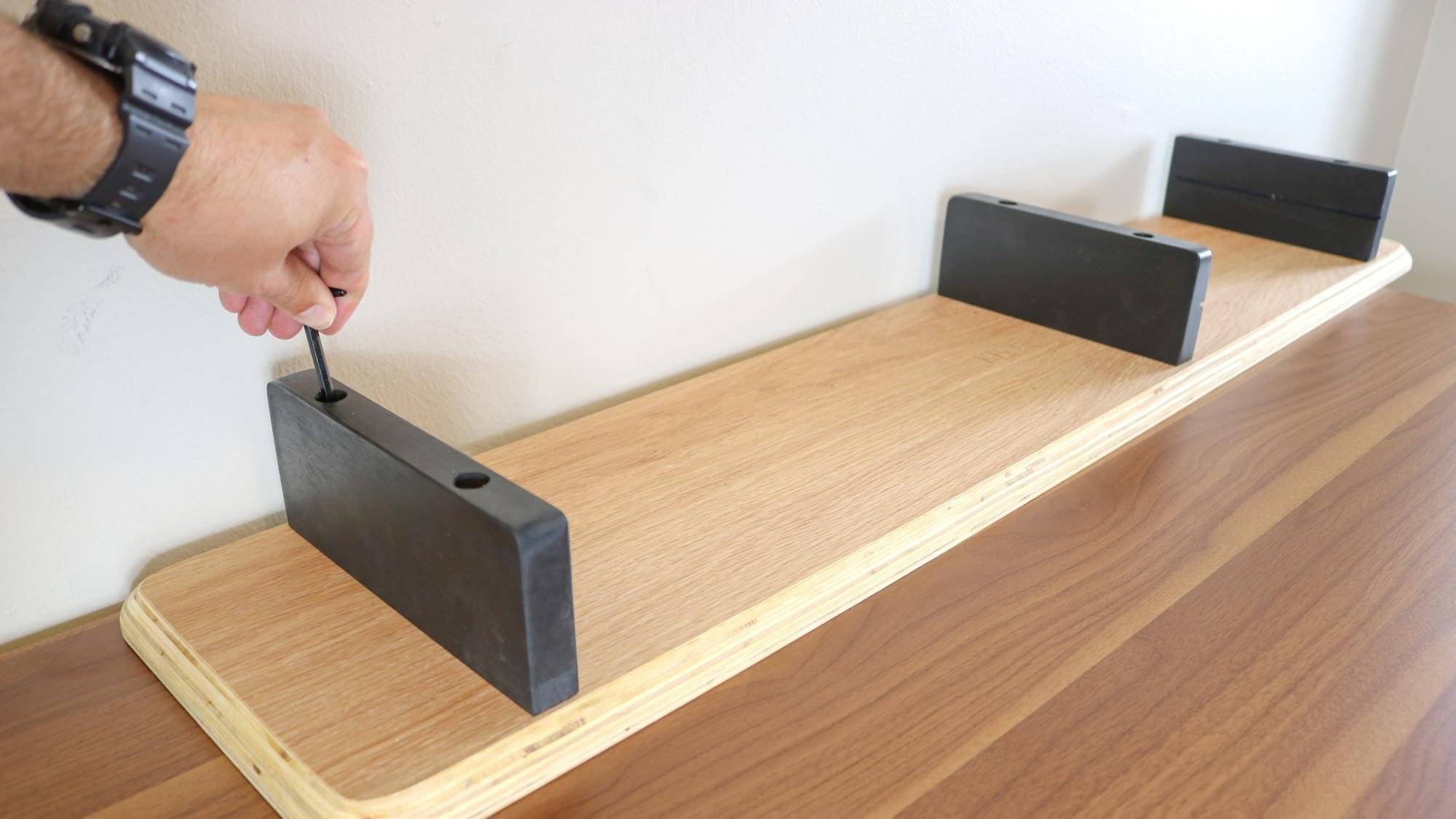 The KIVY shelf being assembled upside down, with a bolt tightened in one of its supports. Image: Tom's Guide.